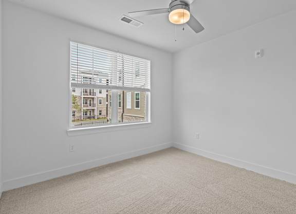 A room with a window showing a view of a building outside.