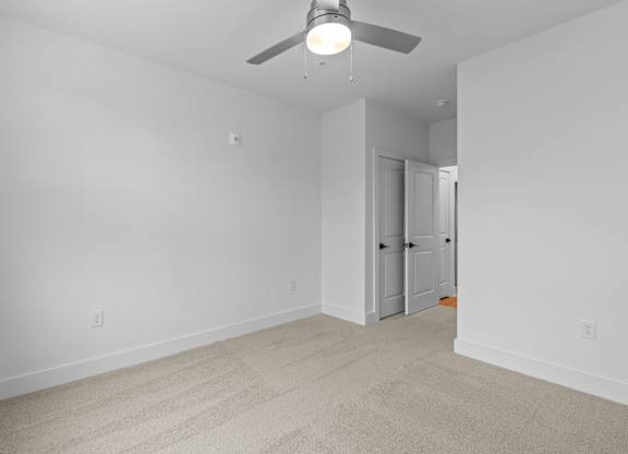 A room with a ceiling fan and carpeted floor.