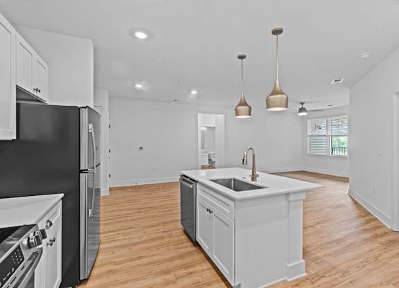 A modern kitchen with a black refrigerator and white cabinets.