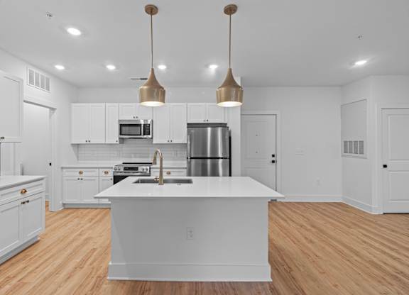 A modern kitchen with a large island and pendant lights.