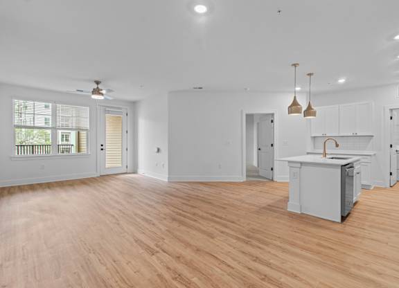 A spacious kitchen with wooden floors and white walls.