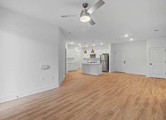 A spacious kitchen with a fan and wooden flooring.