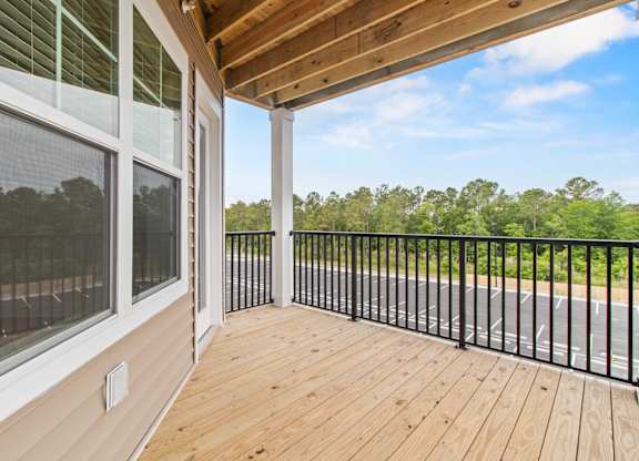 A balcony with a black railing and a wooden floor.