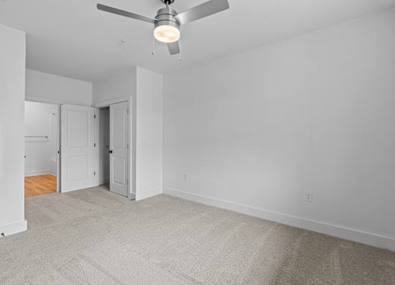 A room with a ceiling fan and carpeted floor.