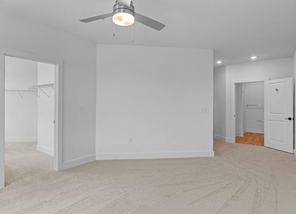A room with a ceiling fan and carpeted floor.