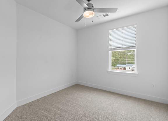A room with a ceiling fan and a window with blinds.