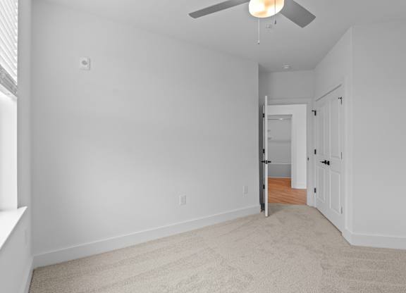 A room with a carpeted floor and a ceiling fan.