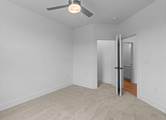 A room with a ceiling fan and a door.