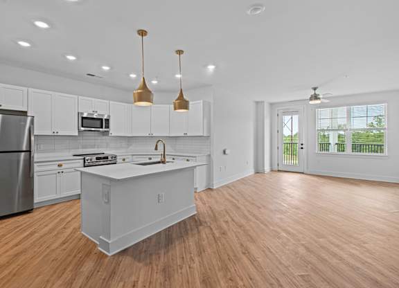 A modern kitchen with a wooden floor and white cabinets.