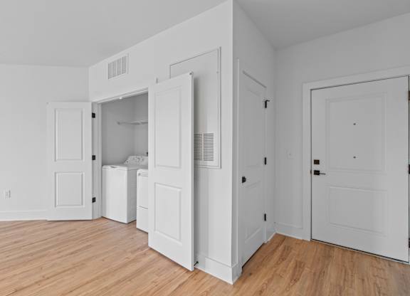 A white room with a washer and dryer in the open door.