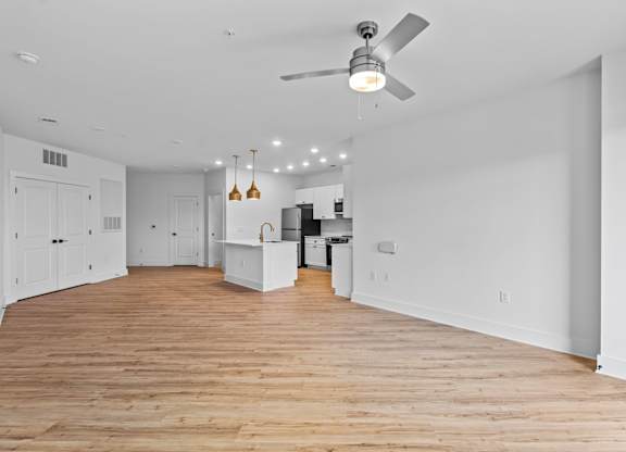 A spacious room with wooden floors and a ceiling fan.