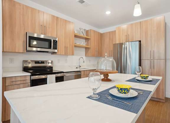 A modern kitchen with a white countertop and wooden cabinets.