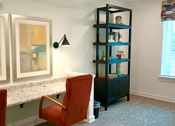 Ovata at Reedy Creek library with a red chair, a black shelf, and a window with blinds.
