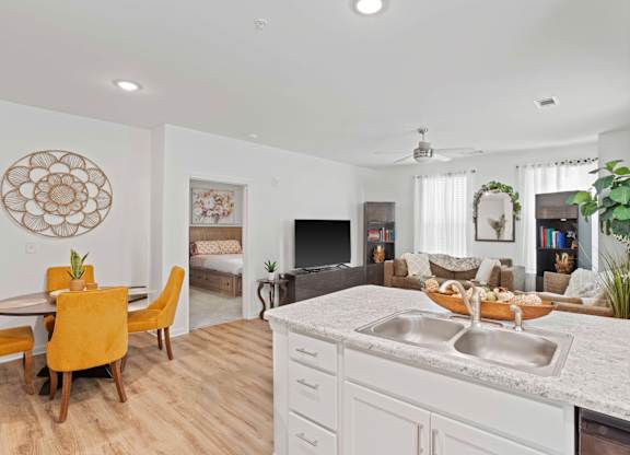 Ovata at Reedy Creek kitchen and connected living room with modern appliances, a peninsula, white cabinetry and LVT flooring.