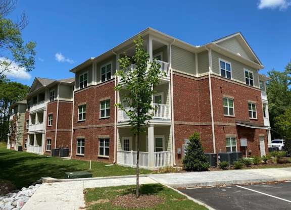 A large brick apartment building with a tree in front.