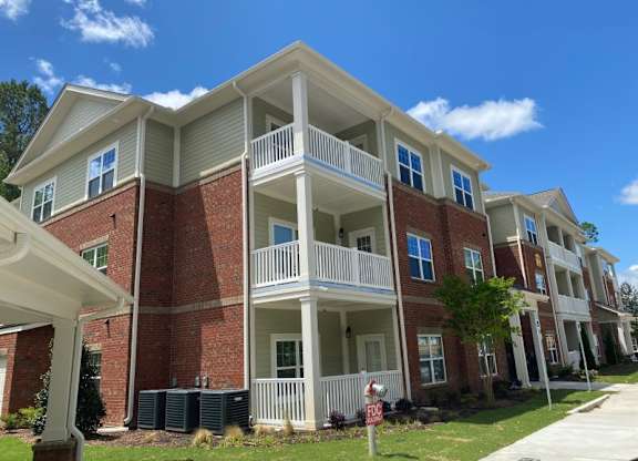 A red brick apartment building with white balconies and a mailbox in front.