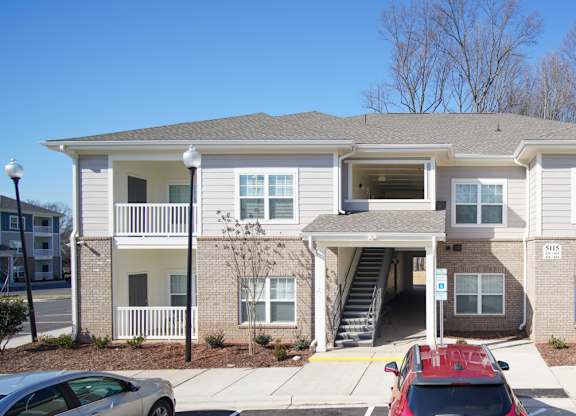 A two-story building with a red car parked in front.