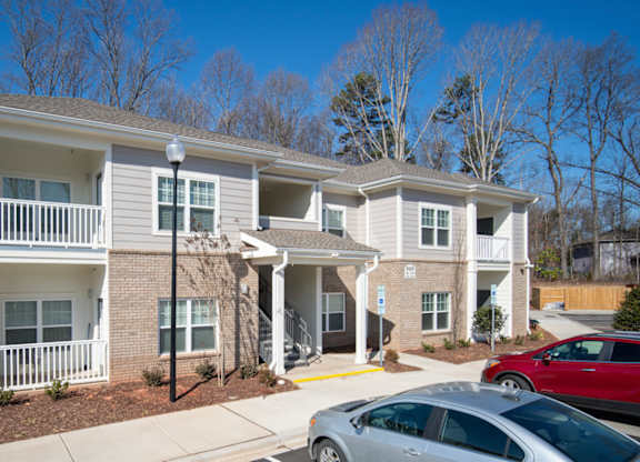 A two-story apartment building with a parking lot in front.