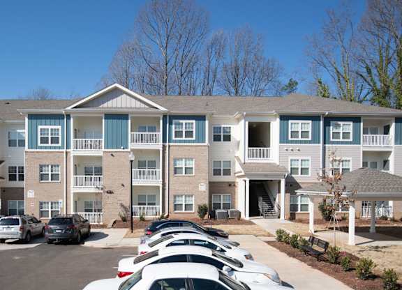 A large apartment complex with a parking lot in front.