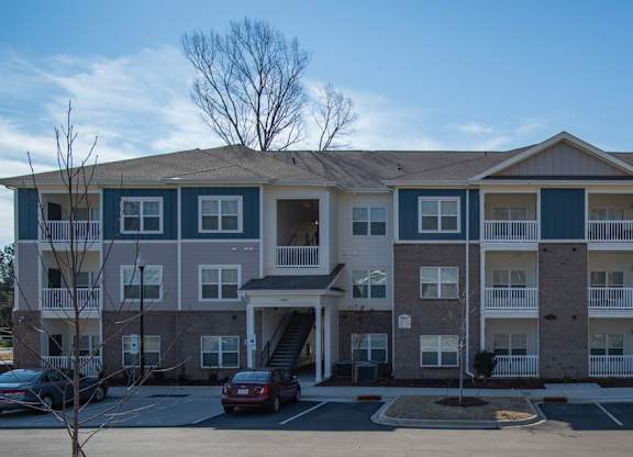 A large apartment building with a parking lot in front.