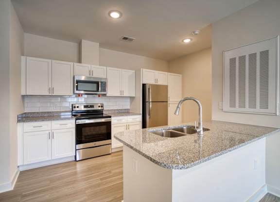 A kitchen with white cabinets and a granite countertop.