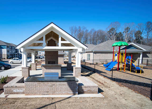 A small building with a porch and a fountain in front of it.