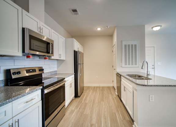 A kitchen with white cabinets and black appliances.