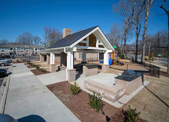 A small building with a black roof is surrounded by a parking lot.
