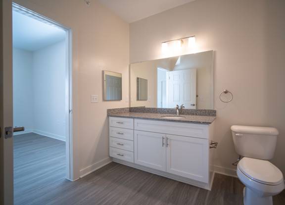 A bathroom with a toilet, sink, and mirror.