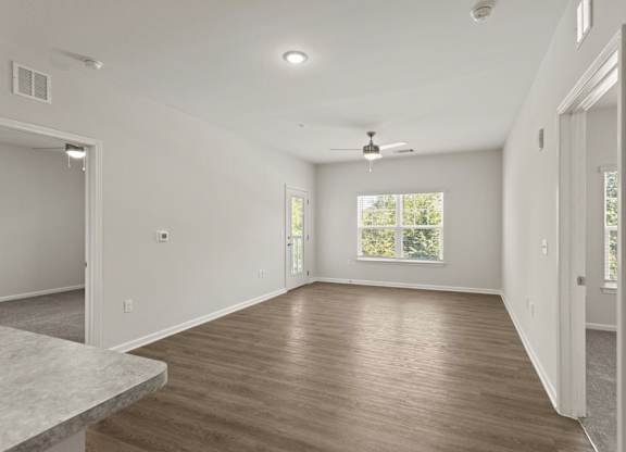 A spacious room with wooden flooring and a ceiling fan.