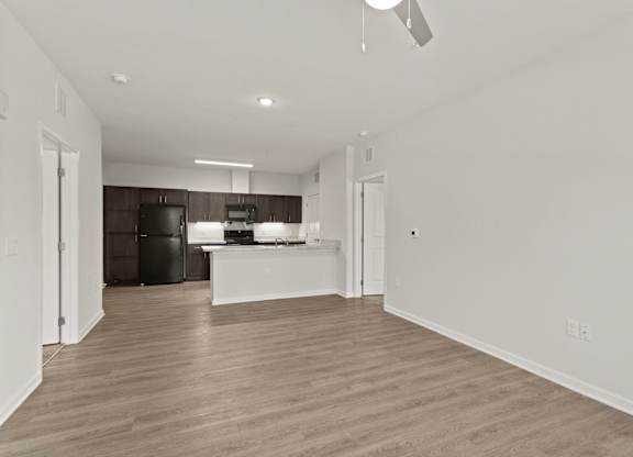 Parkway East Apartments living room and kitchen with black appliances, wood paneling and island.