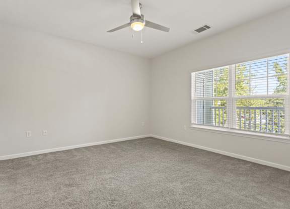 A room with a ceiling fan and a window with blinds.