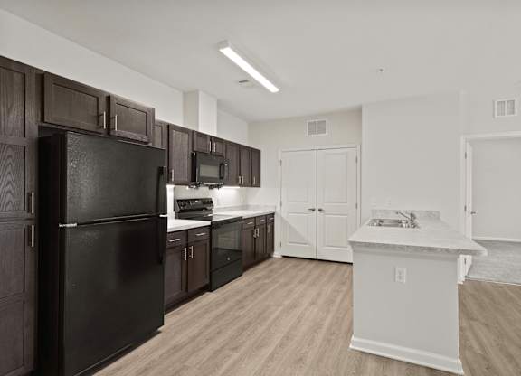 A kitchen with black appliances and wooden cabinets.
