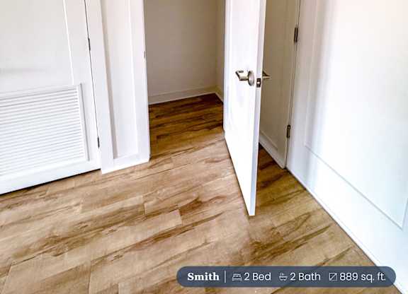 A white door is open to a room with a wooden floor.