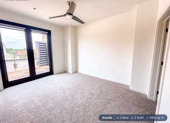 A bedroom with a carpeted floor and a ceiling fan.
