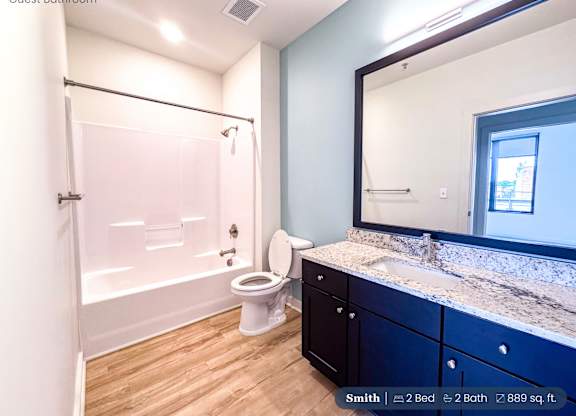 A guest bathroom with a toilet, sink, and mirror.