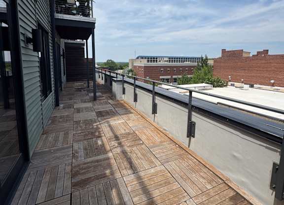 A balcony with a wooden floor and a metal railing.