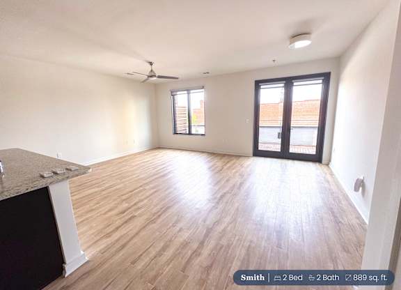 A spacious room with a ceiling fan and a large window.
