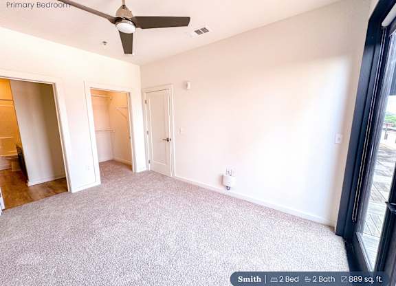 A bedroom with a ceiling fan and two bathrooms.