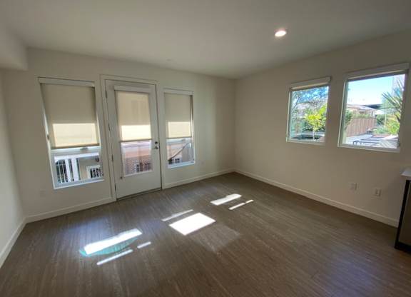 Living room with wood flooring and windows.