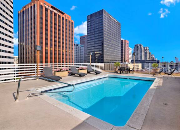 A swimming pool on a rooftop with a city skyline in the background.