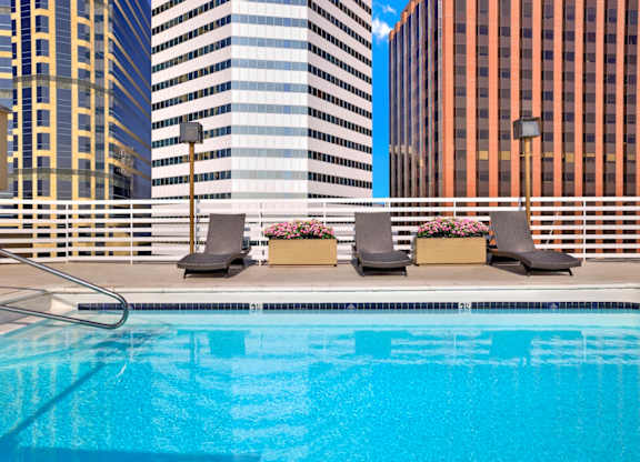 A pool with chairs and flowers in front of a cityscape.