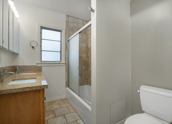 Apartment bathroom with vanity, toilet, and shower tub combo.
