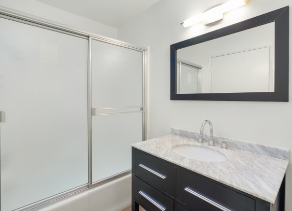 Apartment bathroom with vanity and shower tub combo.