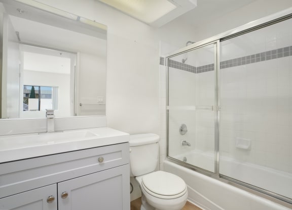Apartment bathroom with vanity, toilet, and shower tub combo.