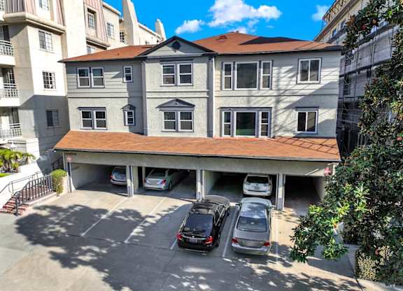 Exterior view of a carport with several cars parked in front.
