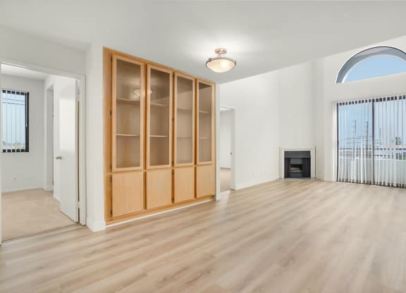 Apartment living room with a fireplace, built-in cabinets and balcony. at Midvale Court, Los Angeles, CA