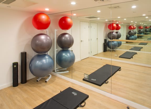 Apartment fitness center with a wall of mirrors, exercise balls, and a stretching mat. at Midvale Court, Los Angeles, CA, 90024