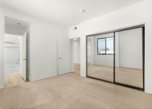 Apartment bedroom with mirrored closet doors and an ensuite bathroom. at Midvale Court, California, 90024