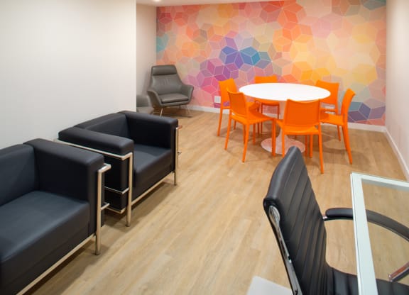 Apartment complex lounge with office furniture and a colorful geometric mural. at Midvale Court, Los Angeles